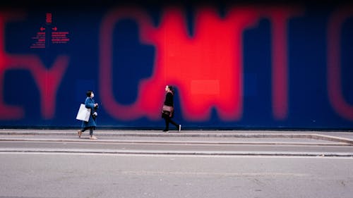 落書きアートの壁と歩道を歩く女性
