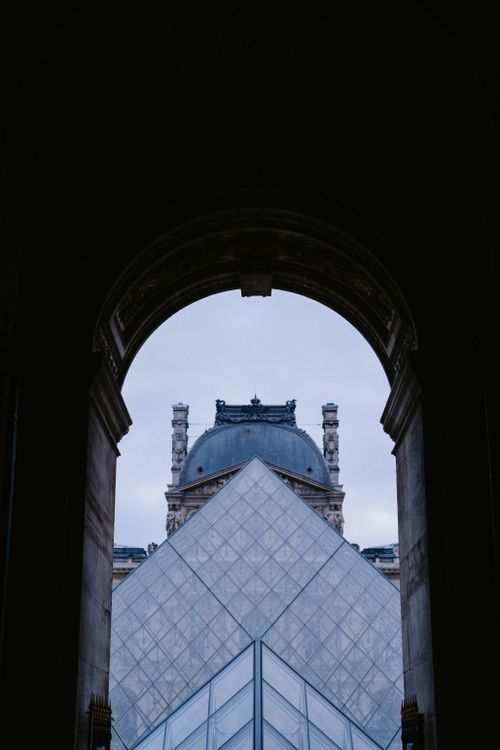 Free The Louvre Museum pyramid framed within a dark archway in Paris, France. Stock Photo