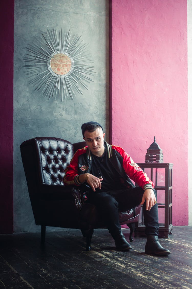 Man In Red And Black Jacket Sitting On A Leather Armchair