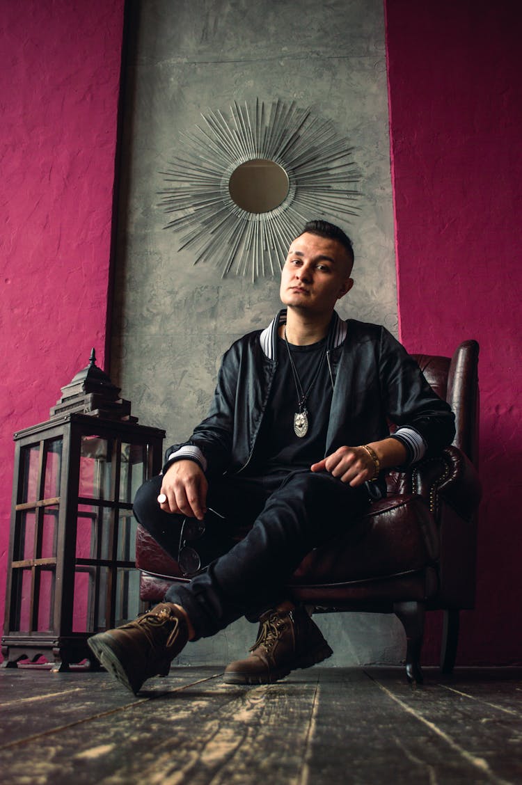 Man In Black Jacket Sitting On A Brown Leather Armchair