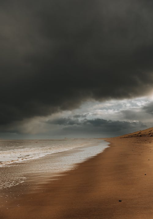 Brown Sand Beach Under Dark Clouds