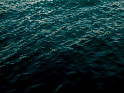 Free Calm ocean waves reflecting sunset light, creating a tranquil and mesmerizing seascape. Stock Photo