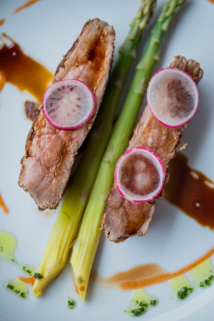 Two Slices Of Rare Tenderloin With Green Asparagus