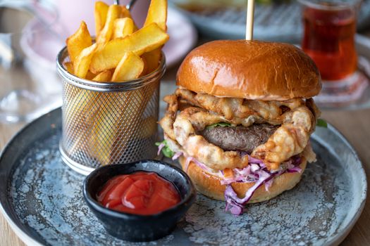 Hamburger gourmet con patatine fritte servito su piatto rustico