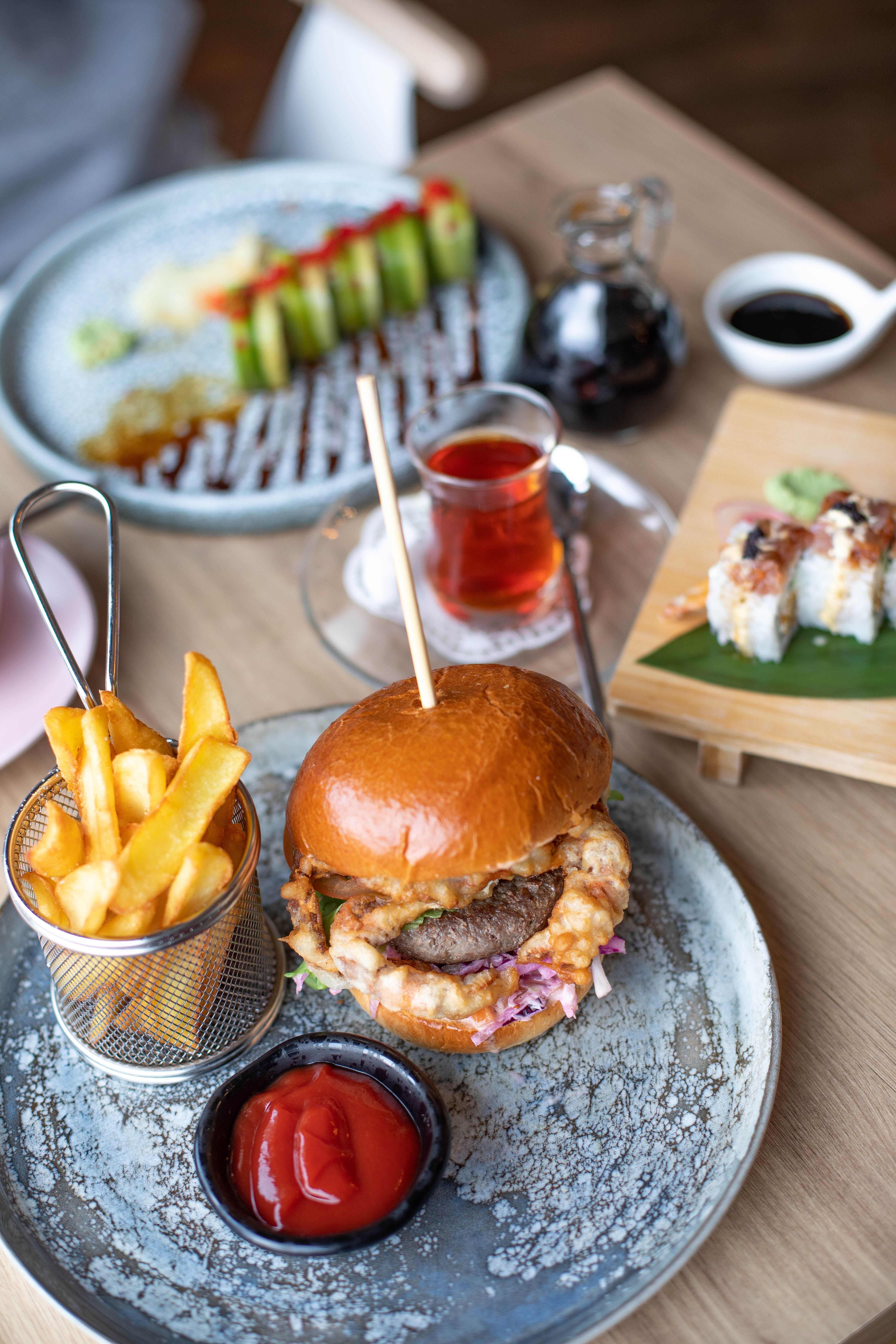 Hamburgare, pommes frites och sushi serverade på ett bord