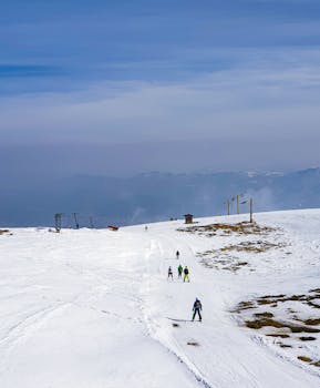 A scenic view of skiers descending a snowy mountain slope during winter on a clear day.