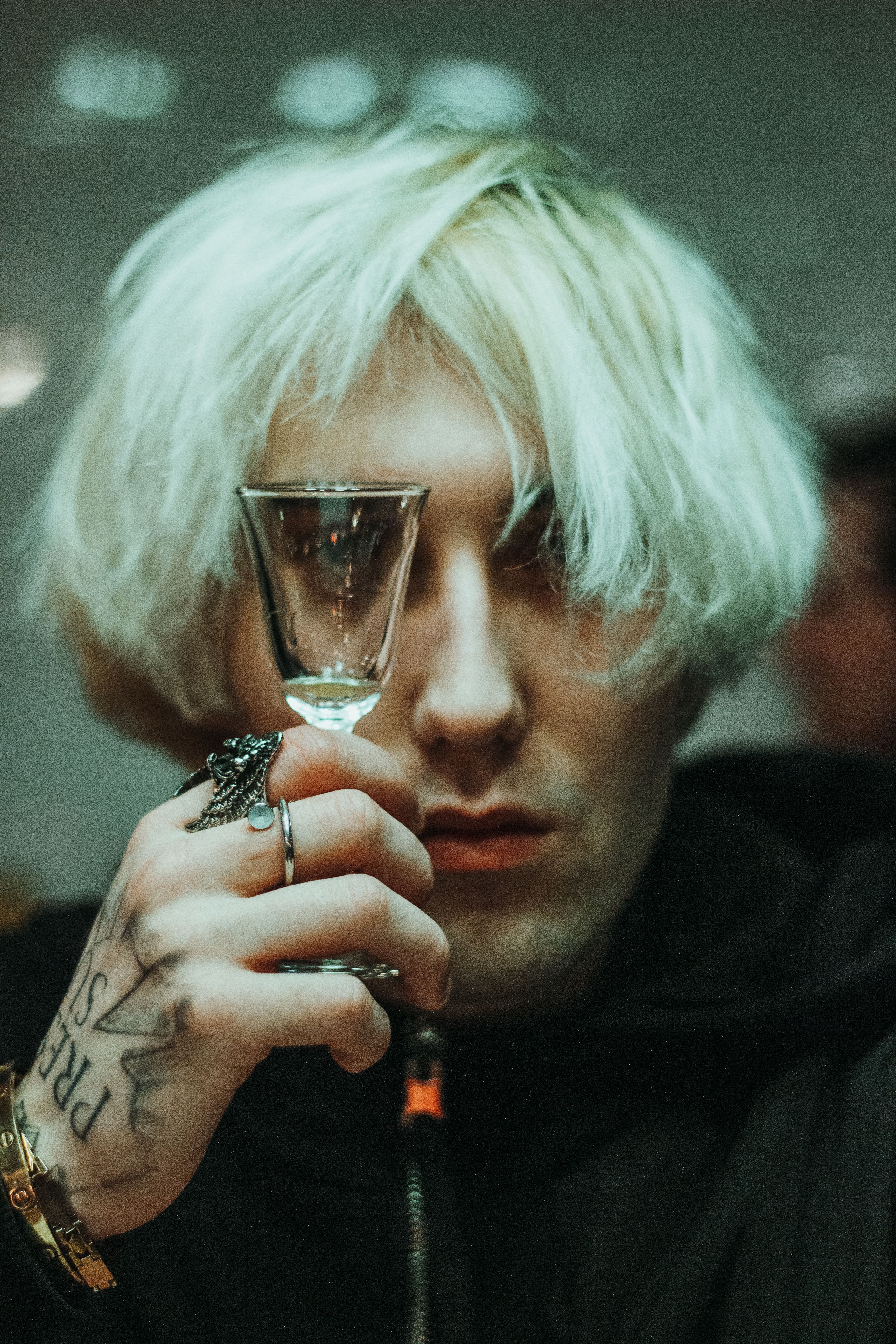 Brooding young man with platinum blonde hair holds a shot glass in Saint Petersburg, Russia.