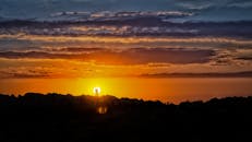 一对情侣的剪影在岩石景观上相拥，映衬着充满活力的日落