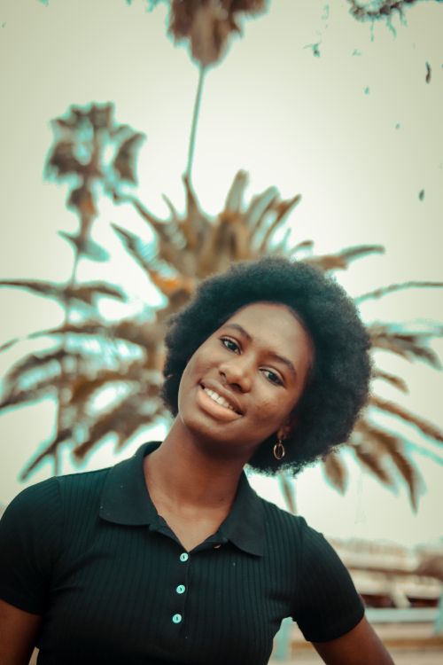 Free Portrait of an African American woman with an afro hairstyle smiling outdoors. Stock Photo