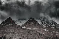 黑暗的风暴云笼罩着雄伟的雪山，营造出戏剧性而阴郁的景观