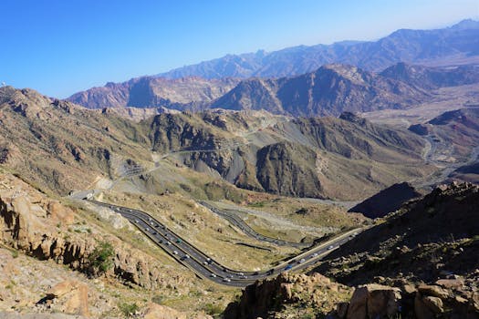 A breathtaking aerial shot of winding roads through majestic mountains under a clear blue sky.