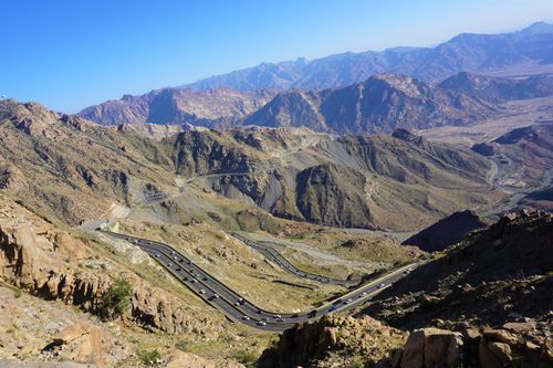 Free A breathtaking aerial shot of winding roads through majestic mountains under a clear blue sky. Stock Photo