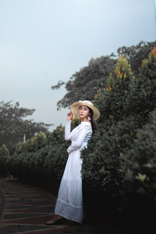 A Woman in White Dress Leaning on Plants