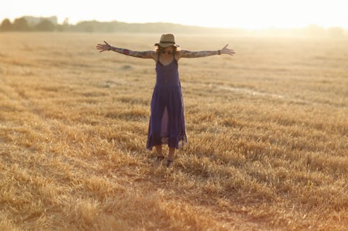 Free Woman in Purple Dress Standing on Brown Grass Field Stock Photo