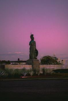 A dramatic view of the Athena statue silhouetted against a purple sunset in Guadalajara.