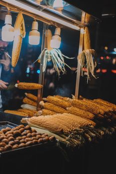A vibrant display of hanging and stacked grilled corn under warm lights at an Istanbul street market.