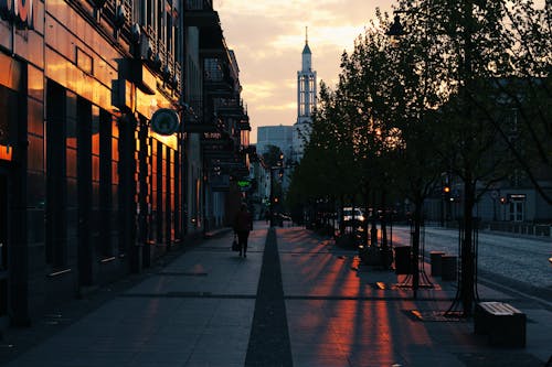 Free Person Walking on Gray Pavement Near Buildings during Golden Hour Stock Photo