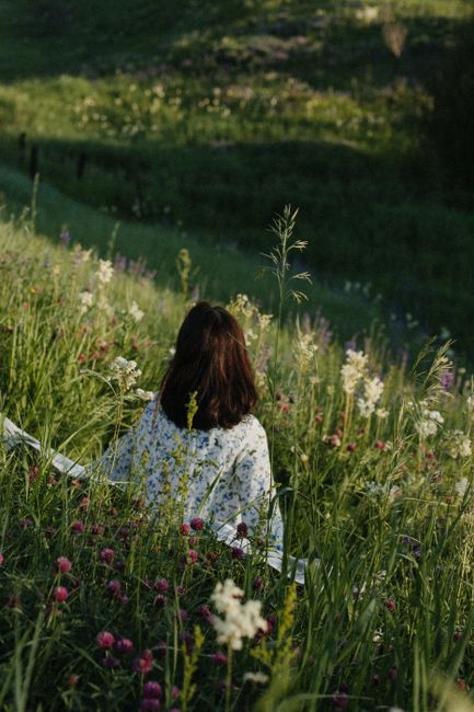 A serene scene of a woman sitting in a lush flower meadow, enjoying nature's tranquility.
