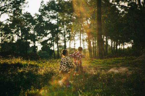 Free Two children running through a sunlit forest during the golden hour, capturing the spirit of adventure and play. Stock Photo