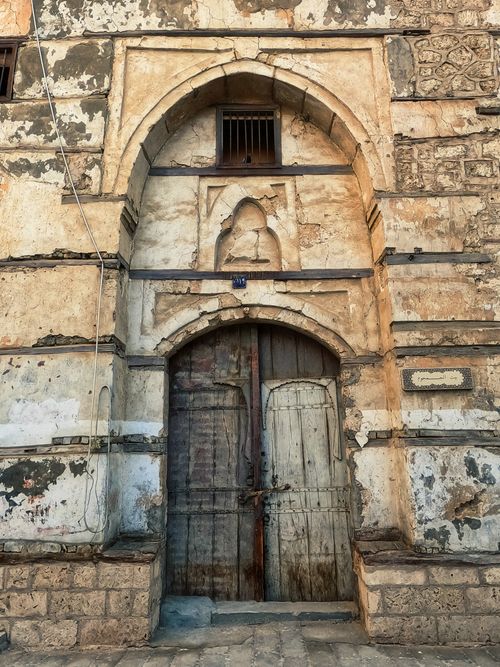 Free Rustic wooden door set in a historic stone building in Jeddah's Old Town, Saudi Arabia. Stock Photo