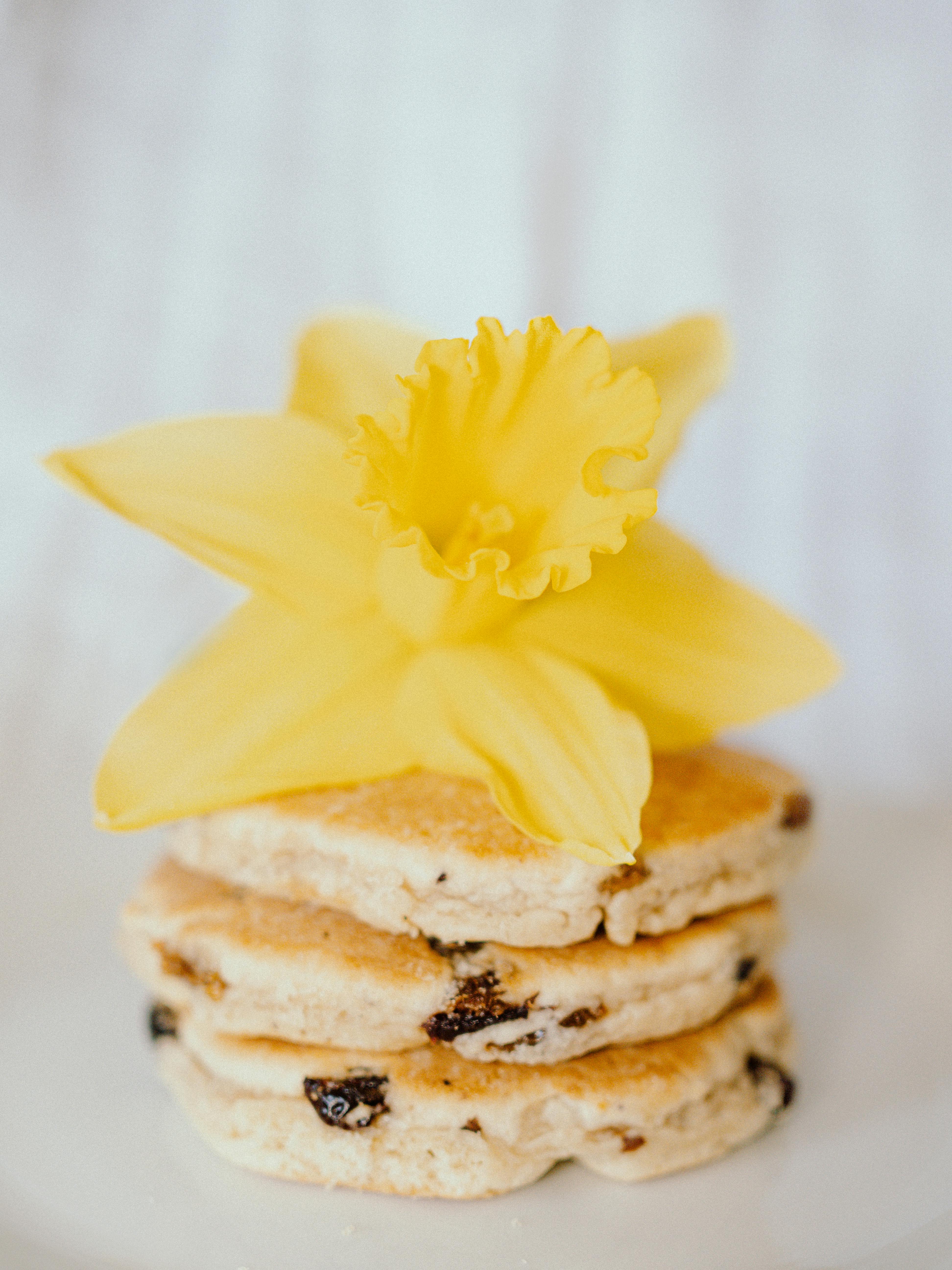 Close-up of stacked Welsh cakes topped with a vibrant yellow daffodil flower.