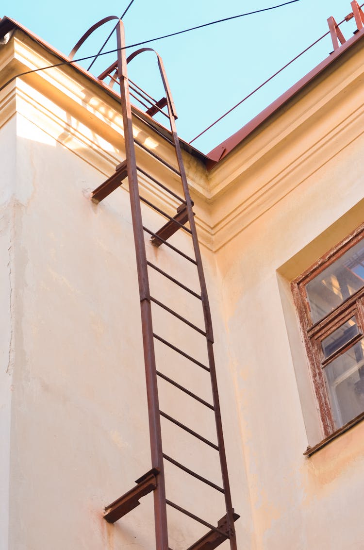 Brown Metal Ladder Attached To Concrete Wall 