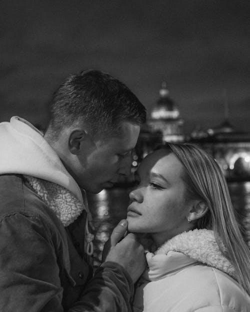 Man in Gray Jacket Holding Woman's Chin