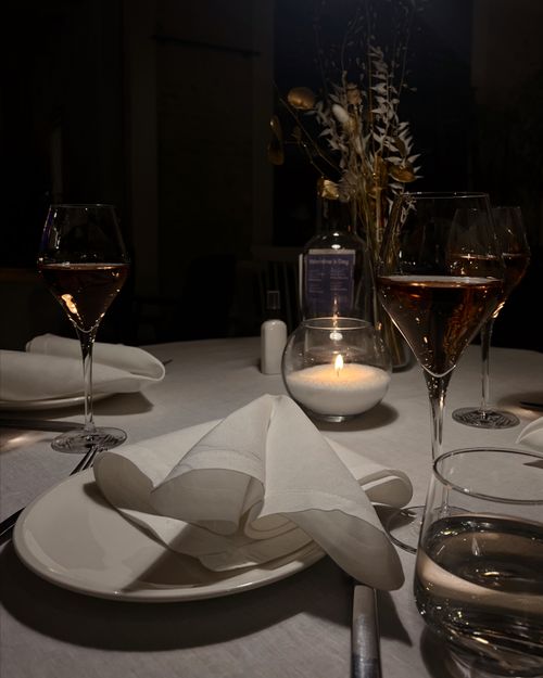 Free Chic dinner table arrangement featuring wine glasses, soft candlelight, and refined tableware. Stock Photo