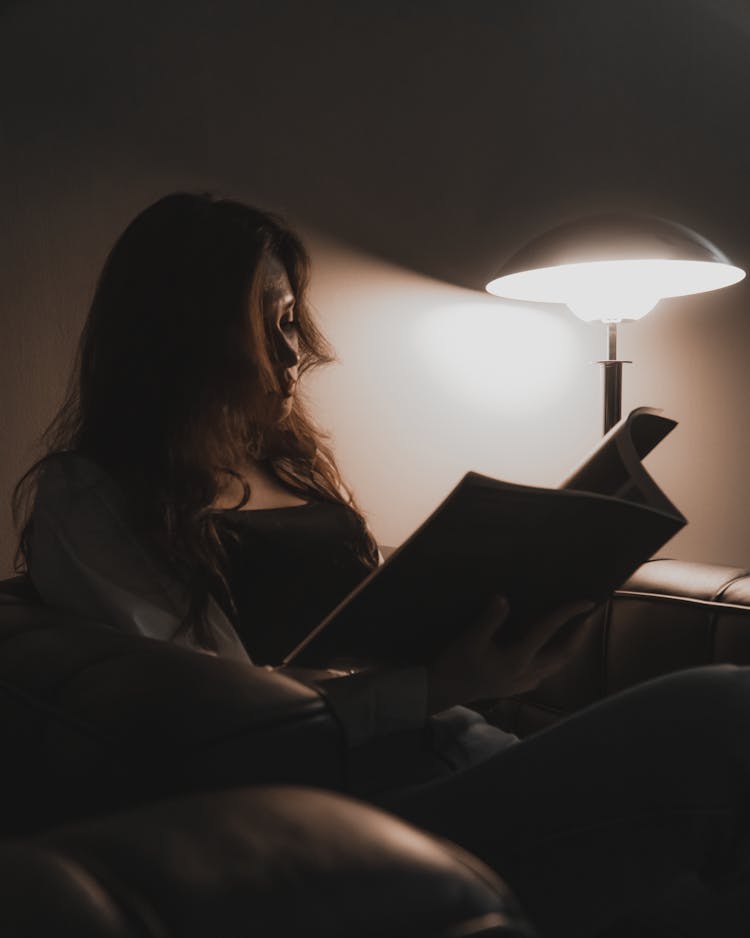 Woman Reading Magazine Beside A Lamp