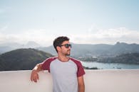 一位戴着太阳镜的男子，在风景优美的山脉背景下，享受着阳光明媚的一天