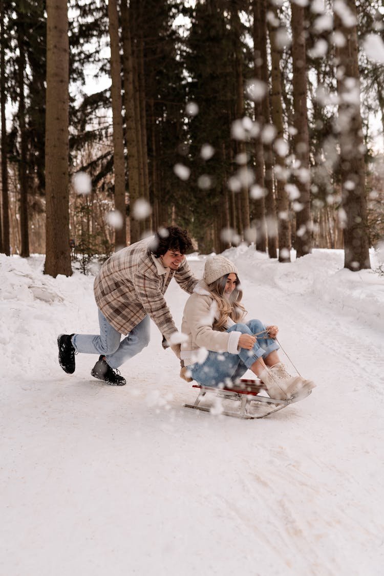 Man Pushing A Woman On Sled