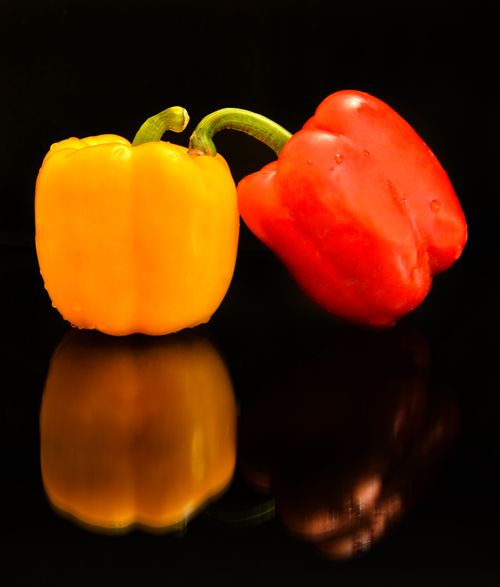 Free Close-up of yellow and red bell peppers with a striking reflection on a black background. Stock Photo