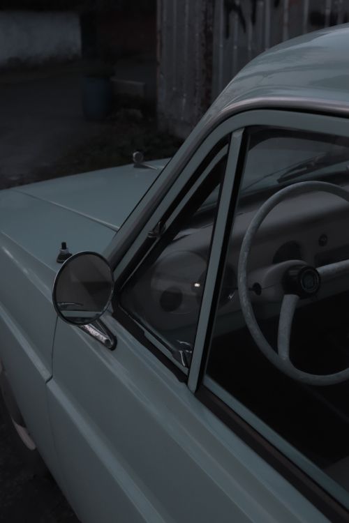 Free A close-up view of a vintage car's side mirror and steering wheel in muted lighting. Stock Photo