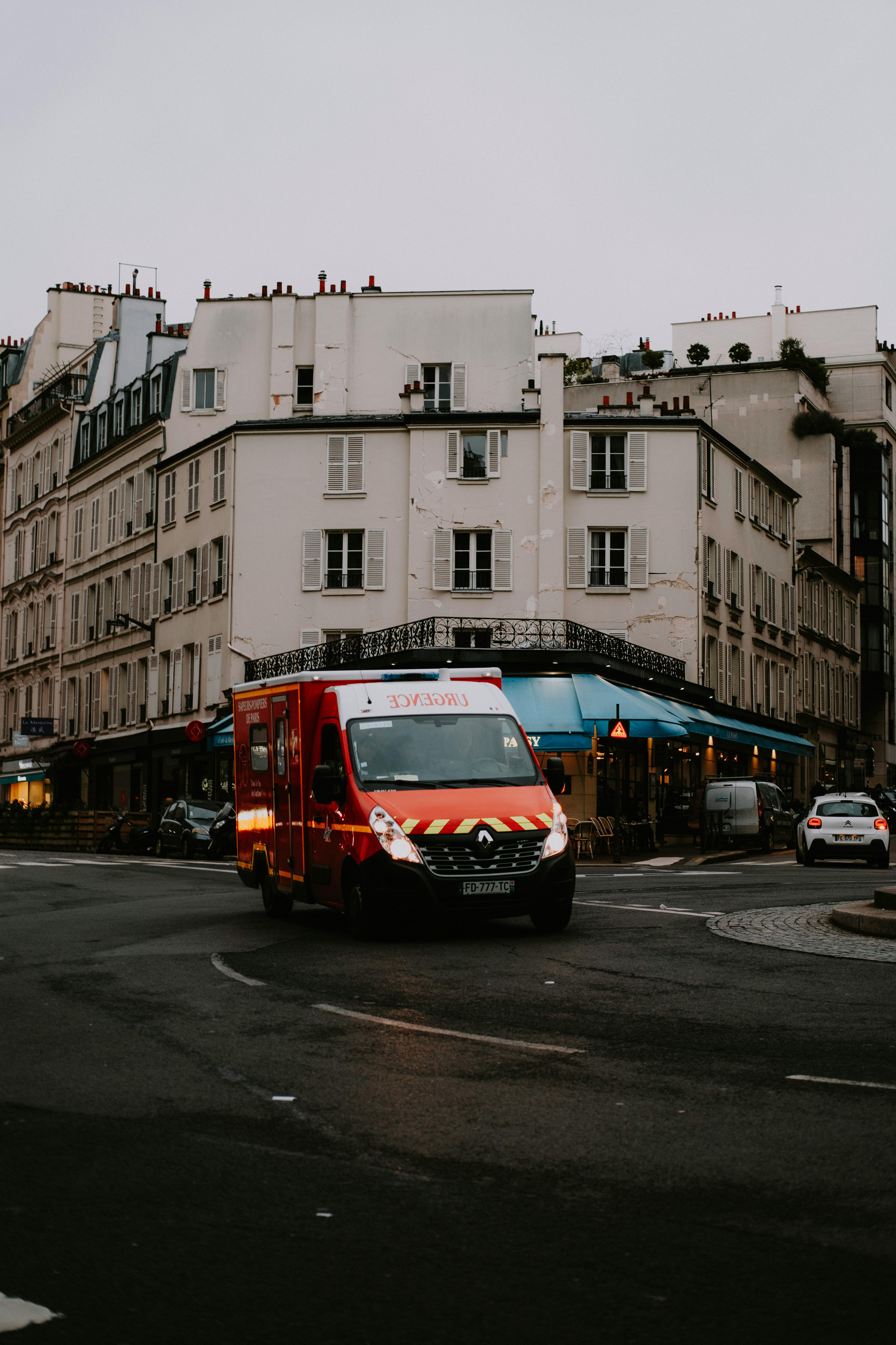 Free Red delivery van on a city street with historical buildings in an urban setting. Stock Photo