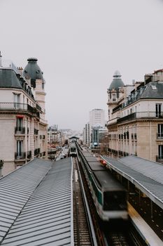 A bustling Paris train station with historic architecture and a moving train, captured from above.