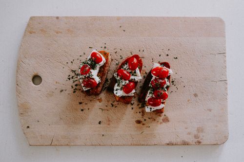 Free Top view of bruschetta with cherry tomatoes, herbs, and cheese on a wooden board. Stock Photo