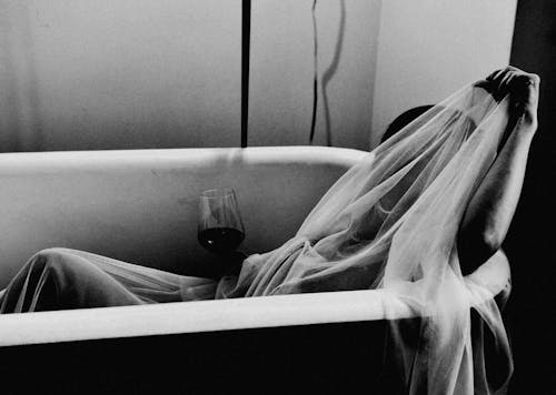 Free Grayscale Photo of a a Person Holding Wine Glass on a Bathtub Stock Photo