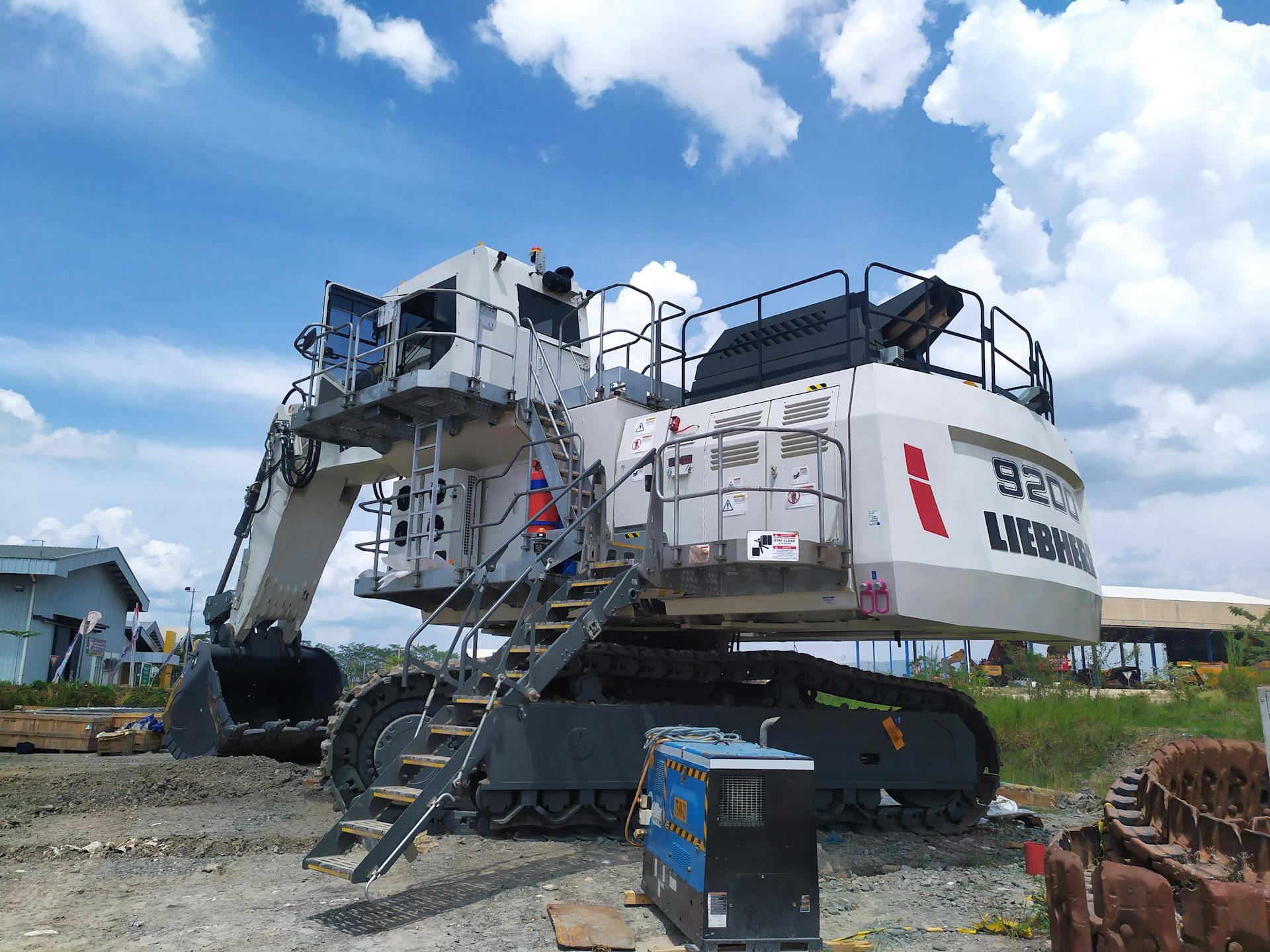 Large Liebherr excavator at an Indonesian construction site under a bright blue sky.