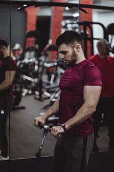 Muscular man with facial hair working out in gym setting, side view captured.