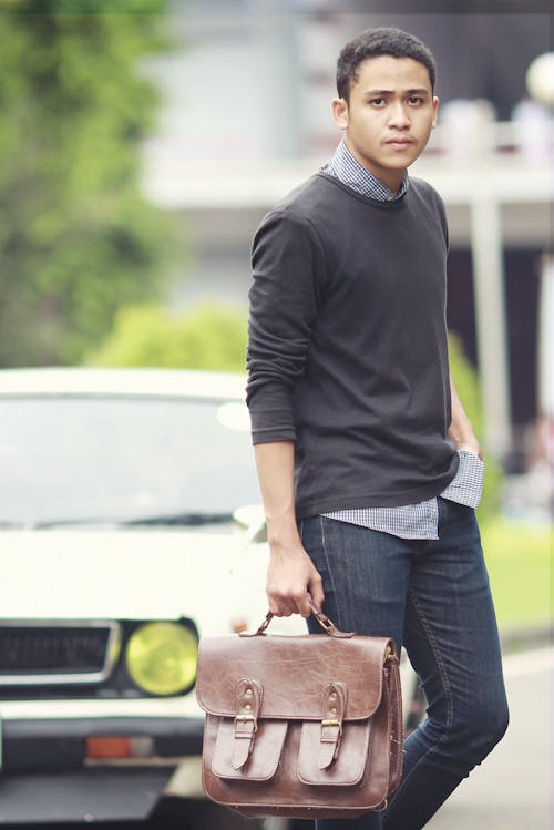 Free A Man in Black Long Sleeves and Denim Jeans Holding a Handbag Stock Photo