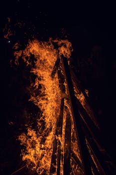 A dramatic close-up of a vibrant bonfire with flames against a dark night backdrop.