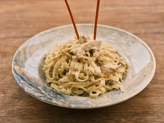 Creamy fettuccine with pieces of chicken and cracked pepper on a pale blue ceramic plate