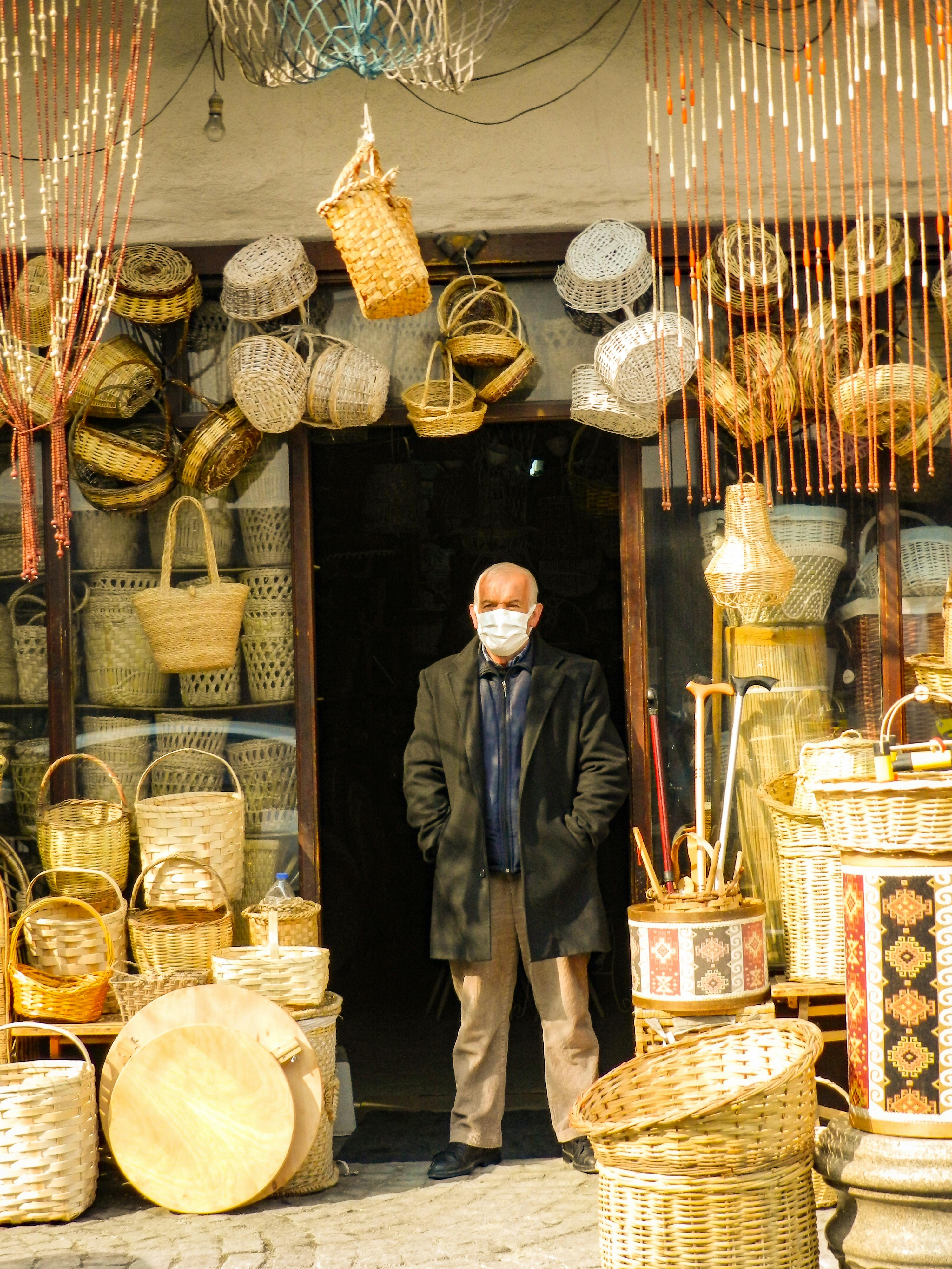 man in black coat surrounded by woven baskets