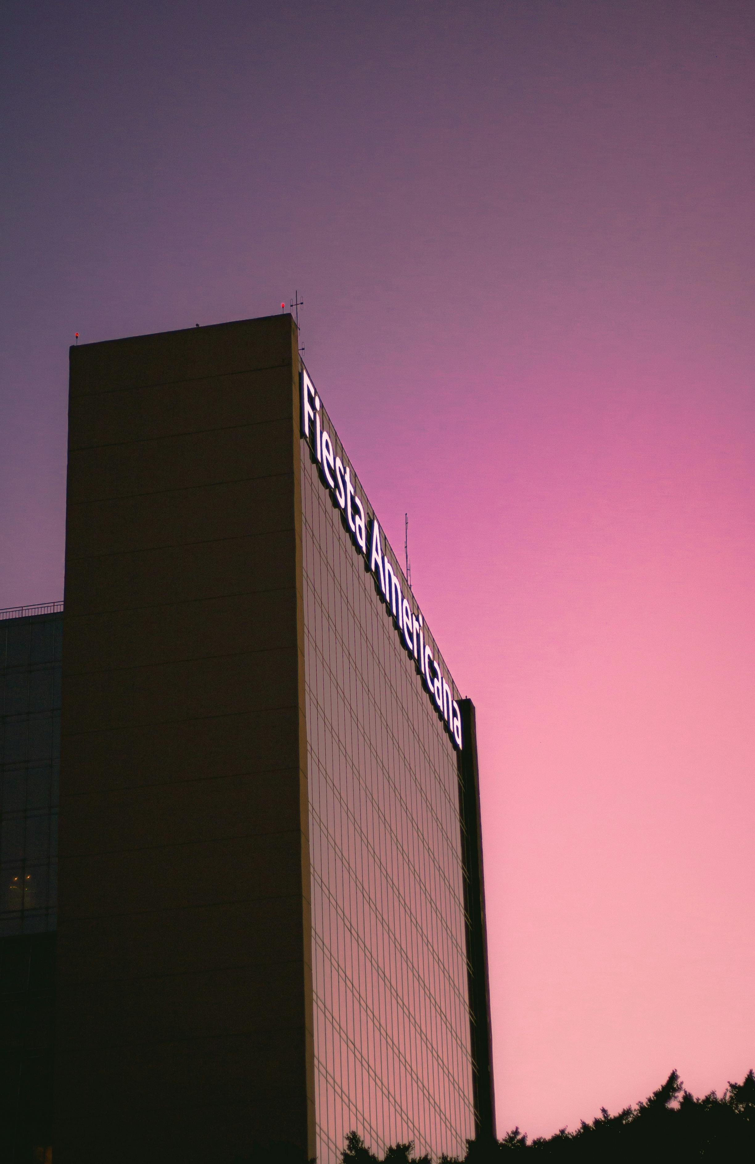 Low angle view of Fiesta Americana Hotel facade with pink twilight sky backdrop.