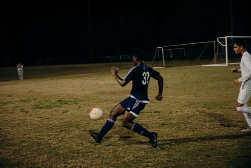 Free Two players compete fiercely during a nighttime football match on a grass field. Stock Photo
