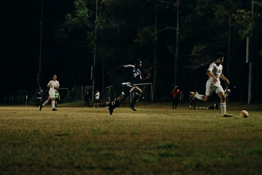 Players competing in a soccer match at night under bright stadium lights.