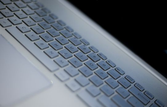 Detailed view of a white laptop keyboard with ambient lighting.