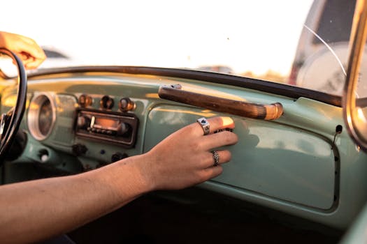 A close-up of a vintage car dashboard with a hand wearing rings adjusting controls.