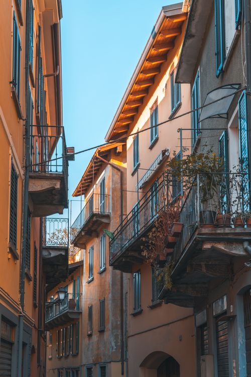 Free A picturesque narrow alley with historic buildings and balconies in Italy, basking in warm sunlight. Stock Photo