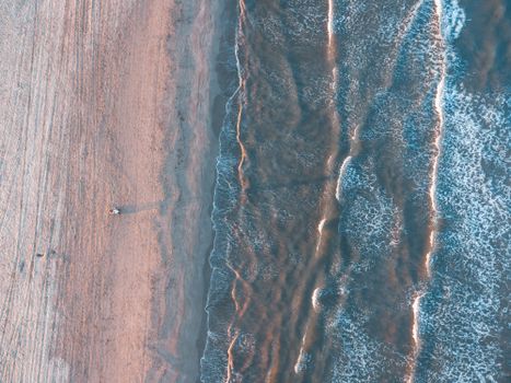 Stunning aerial view of ocean waves lapping on a secluded sandy beach with ample copy space.